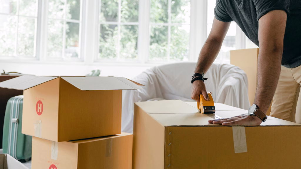 Person beim Umzug verpackt Kartons in heller Wohnung – Umzugsvorbereitung für neues Zuhause